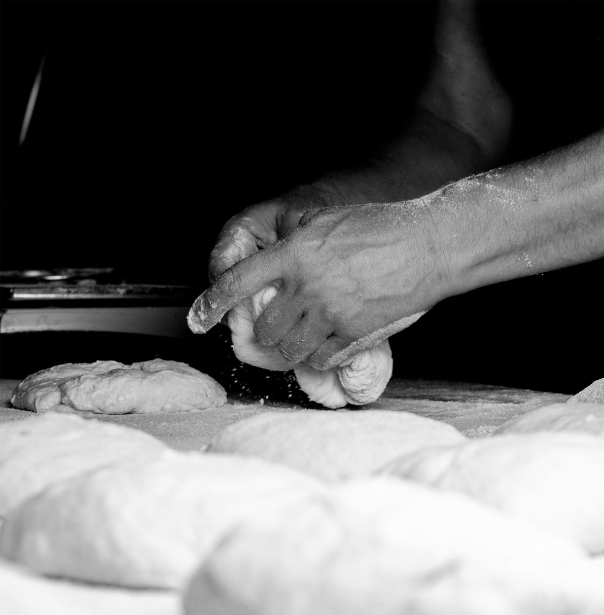 Una foto en blan i negre on es veuen unes mans donant forma a una massa