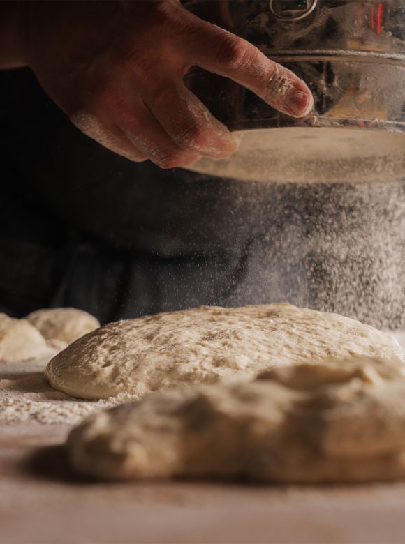 Alg&uacute; posa farina per sobre d'unes porcions de massa